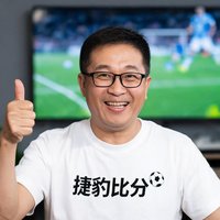 一位戴眼镜的中年男性足球迷，穿着捷豹比分主题T恤，竖起大拇指