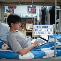 大学生小周在宿舍床上用笔记本电脑查看捷豹比分的篮球数据页面